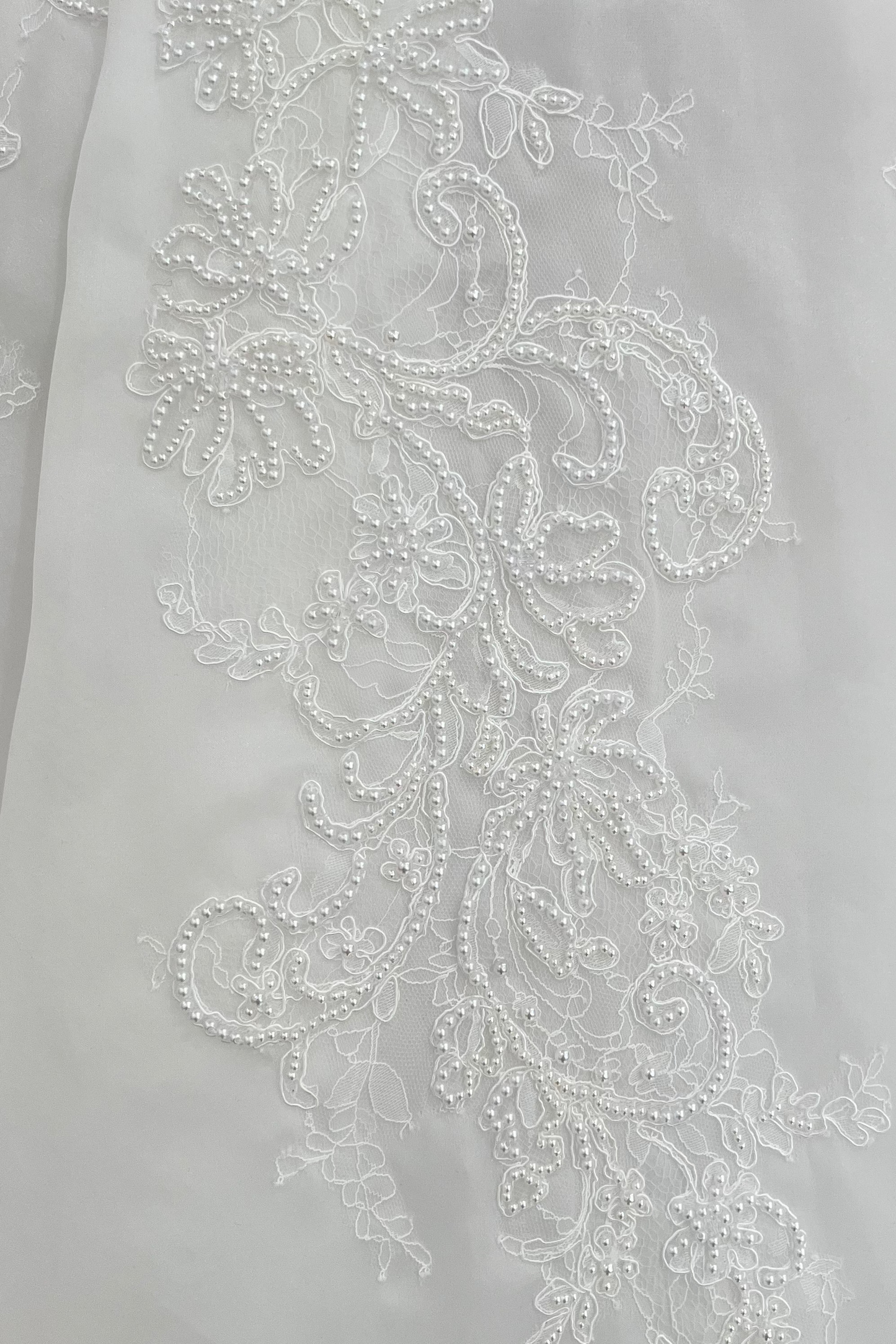 Close-up detail of the Claudia wedding dress featuring Chantilly lace with intricate pearl-embellished floral embroidery on organza.