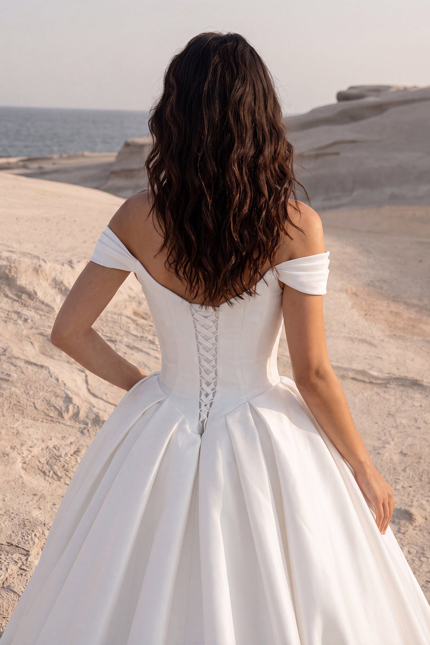 Close-up back view of the Eliana wedding dress featuring an off-the-shoulder neckline, a lace-up corset back, and a voluminous Mikado ball gown skirt.