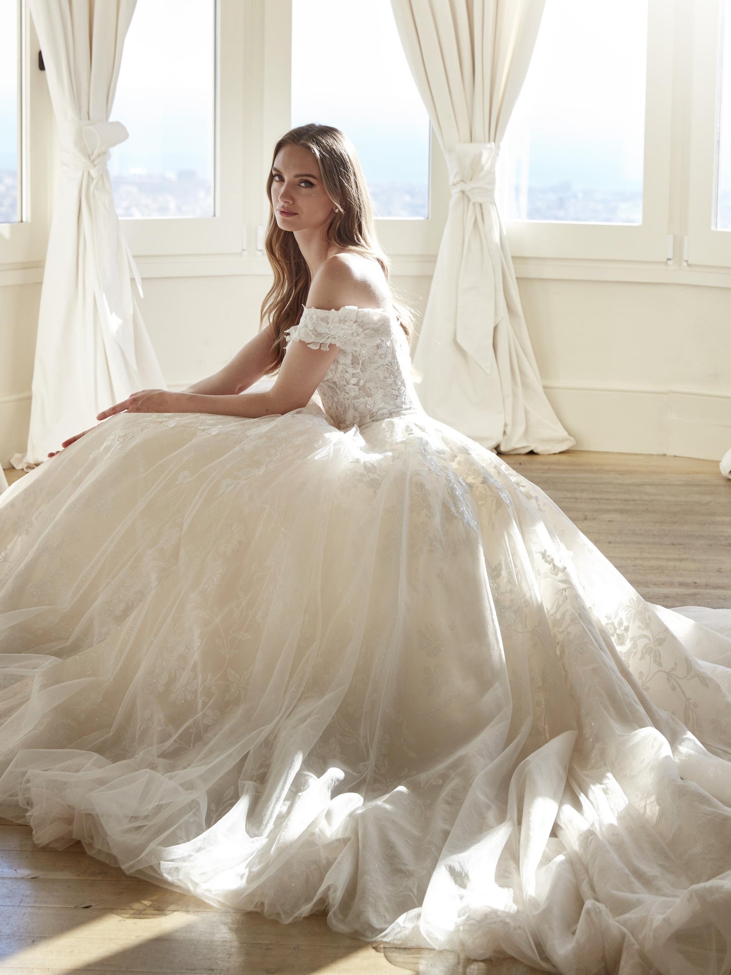 Closeup side view of the Juddy princess wedding dress showcasing off-the-shoulder floral straps and a voluminous glitter lace skirt.