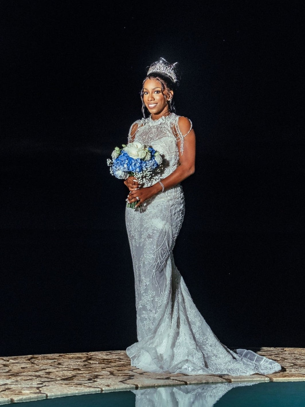 Bride Brittany in a beaded mermaid wedding dress by Krismil Bridal, holding a blue and white bouquet at Ocean Cliff Hotel in Negril, Jamaica.