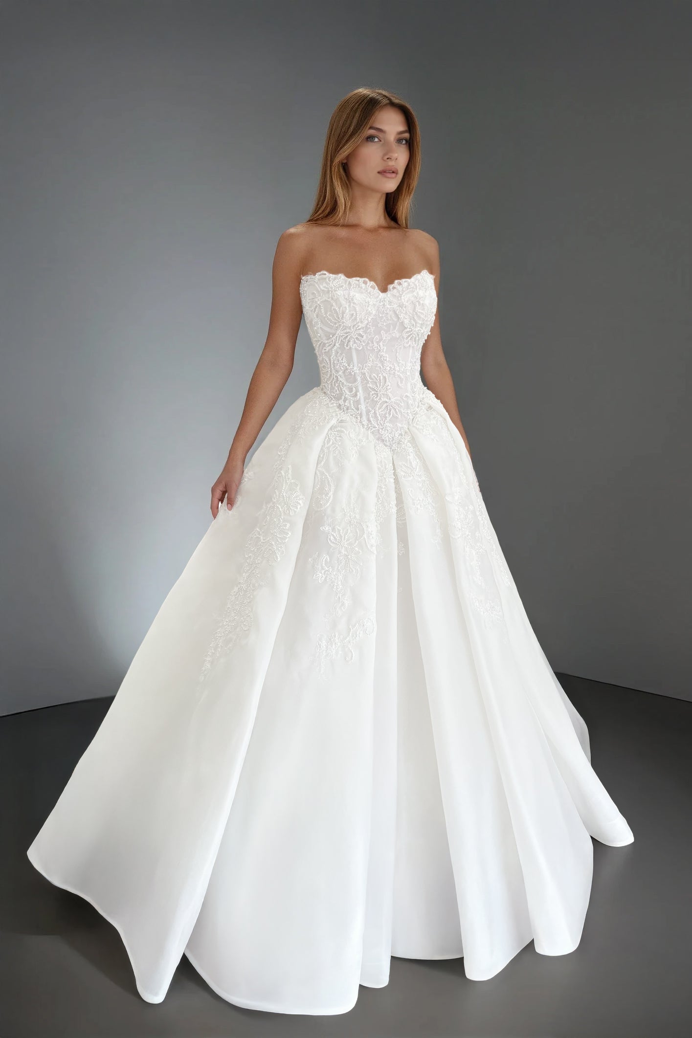 Front view of the Claudia wedding dress featuring a strapless corset bodice with a basque waist and intricate pearl-embellished lace over a voluminous organza ball gown skirt.