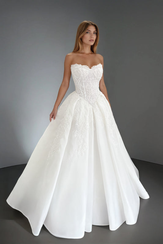 Front view of the Claudia wedding dress featuring a strapless corset bodice with a basque waist and intricate pearl-embellished lace over a voluminous organza ball gown skirt.