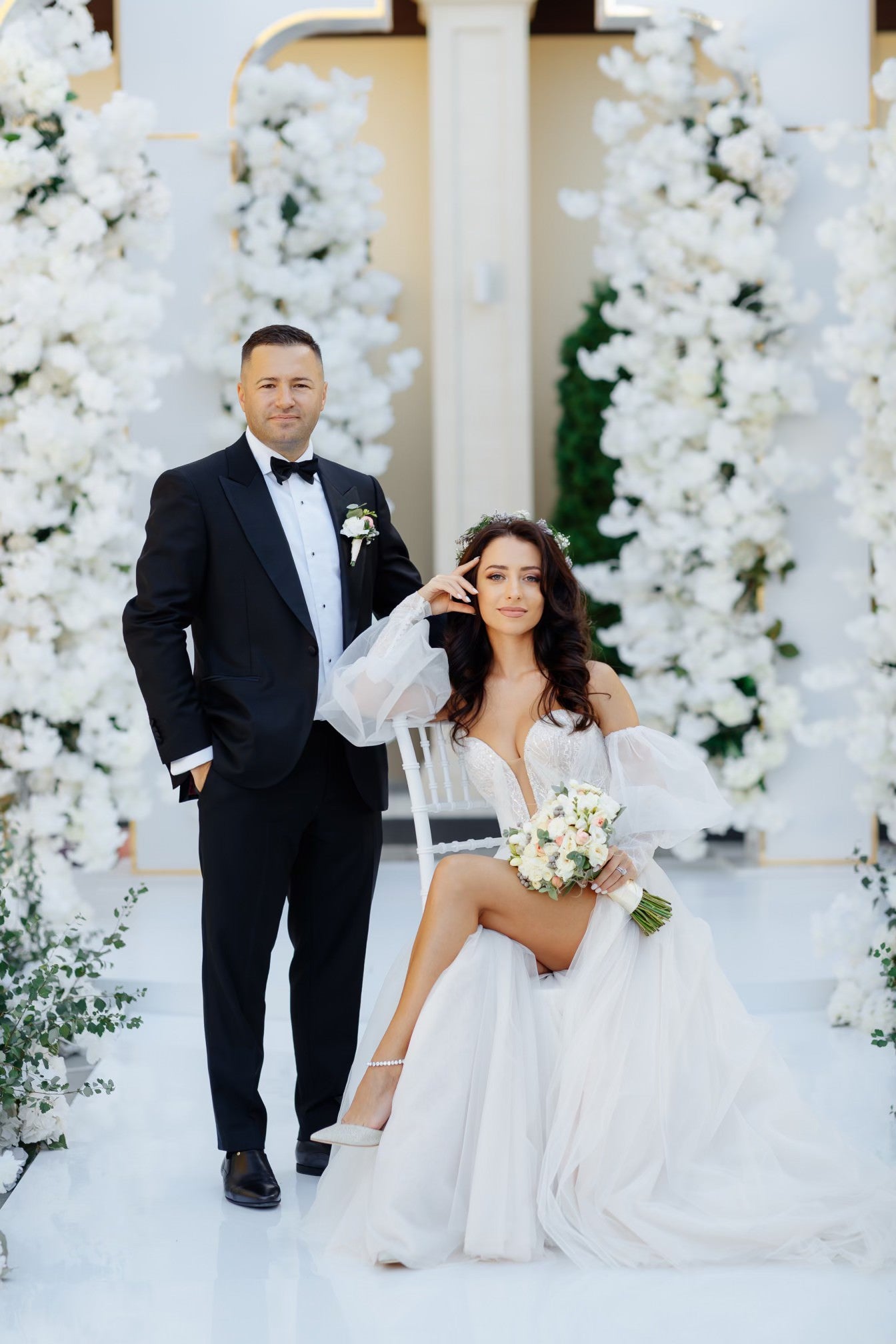 Bride Doina in an off-the-shoulder tulle wedding dress by Krismil Bridal, posing with her husband Adrian during their wedding.