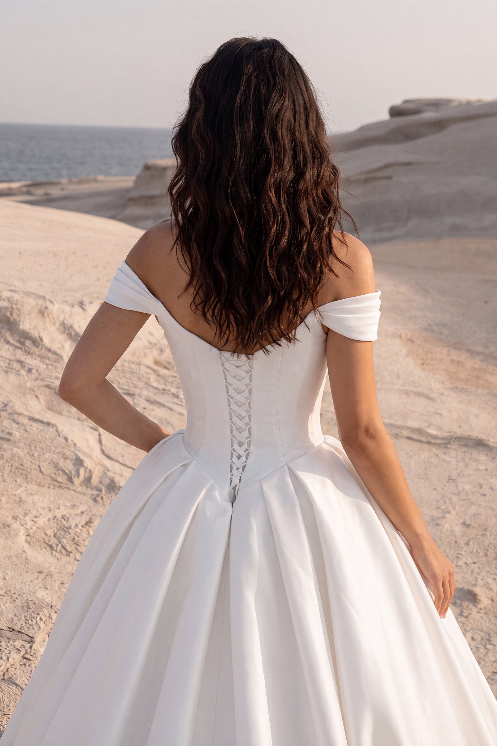 Close-up back view of the Eliana wedding dress featuring an off-the-shoulder neckline, a lace-up corset back, and a voluminous Mikado ball gown skirt.