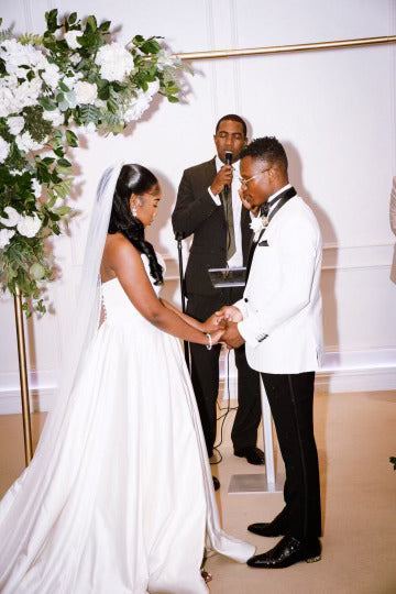 Bride Jessica and her husband exchanging vows during their New York wedding, with Jessica wearing a satin gown by Krismil Bridal.