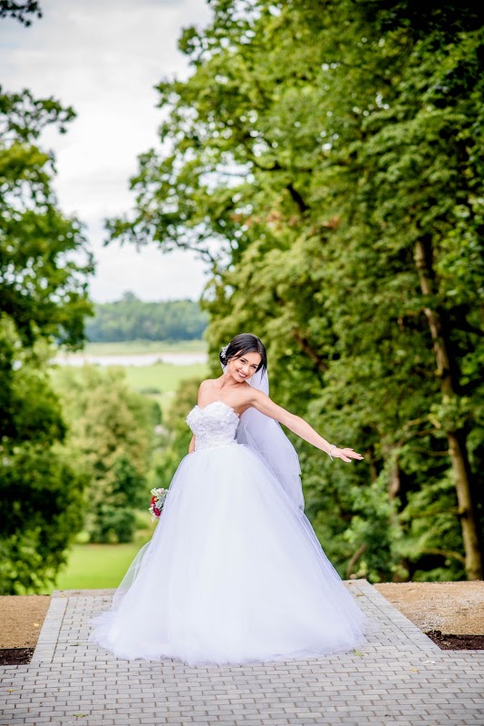 Bride Juste in a strapless ball gown wedding dress by Krismil Bridal, smiling and posing outdoors during her wedding in Lithuania.