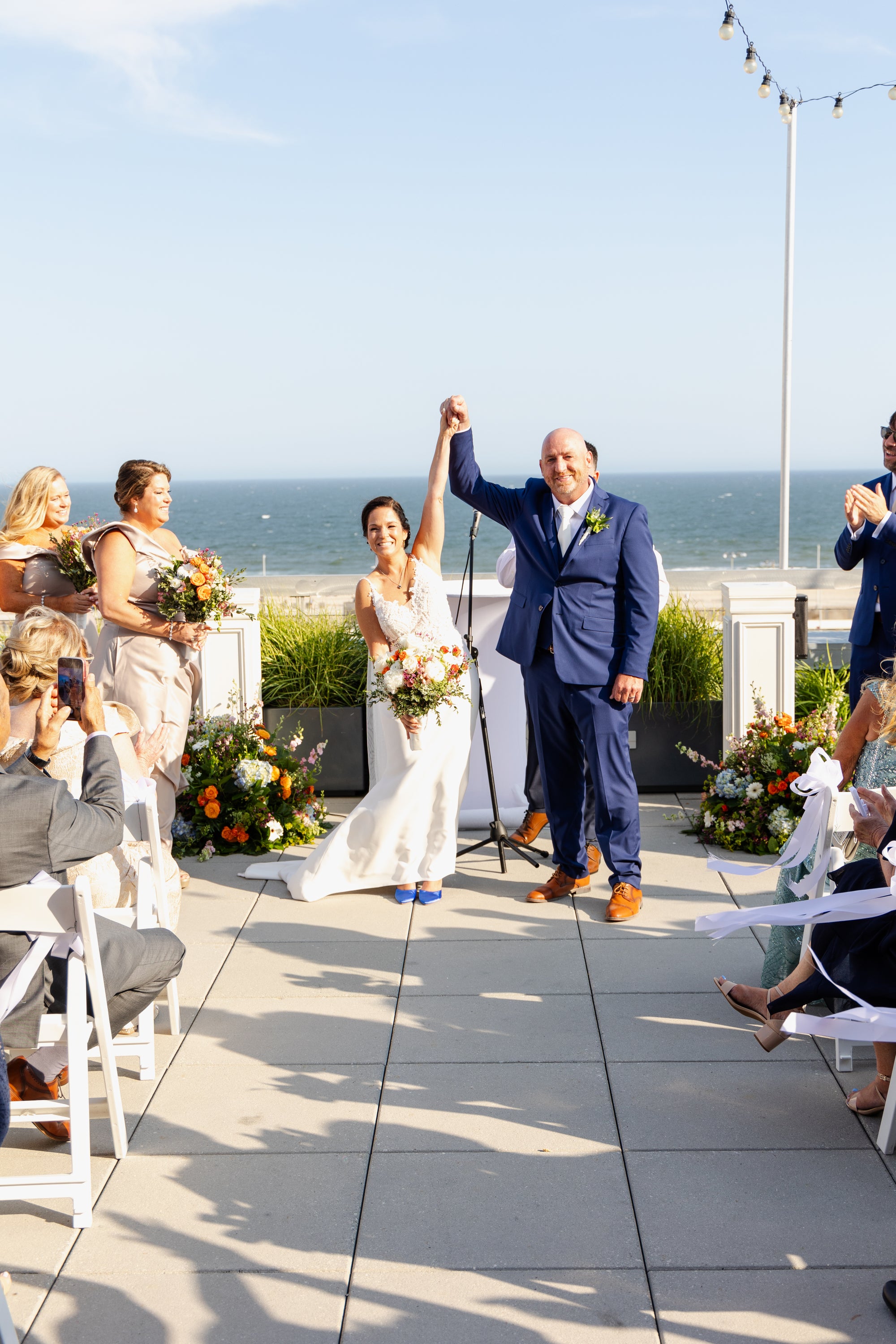 Bride Leigh Ann in a crepe wedding dress by Krismil Bridal, celebrating with her husband Kenneth at their beachside wedding.