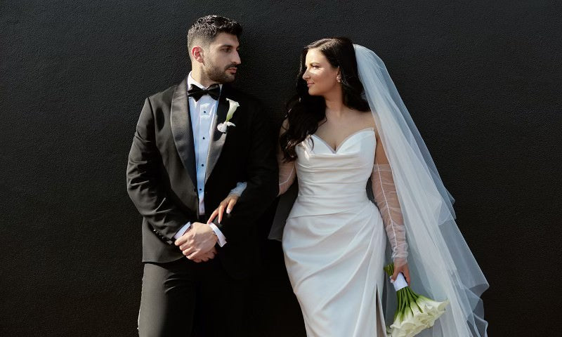 Bride Valerie in a strapless satin mermaid wedding dress by Krismil Bridal, standing with her husband Pirouz on their wedding day. 